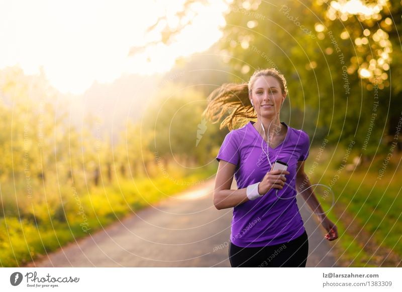 Frau, die Musik beim Joggen auf einer Straße hört Lifestyle Glück Sommer Sport Erwachsene Landschaft Herbst Baum Blatt Park T-Shirt Bewegung Fitness hören