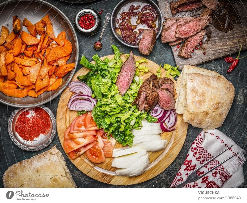 Zutaten für Sandwich mit medium gebratenem Steak. Lebensmittel Fleisch Gemüse Salat Salatbeilage Kräuter & Gewürze Öl Ernährung Mittagessen Abendessen Büffet