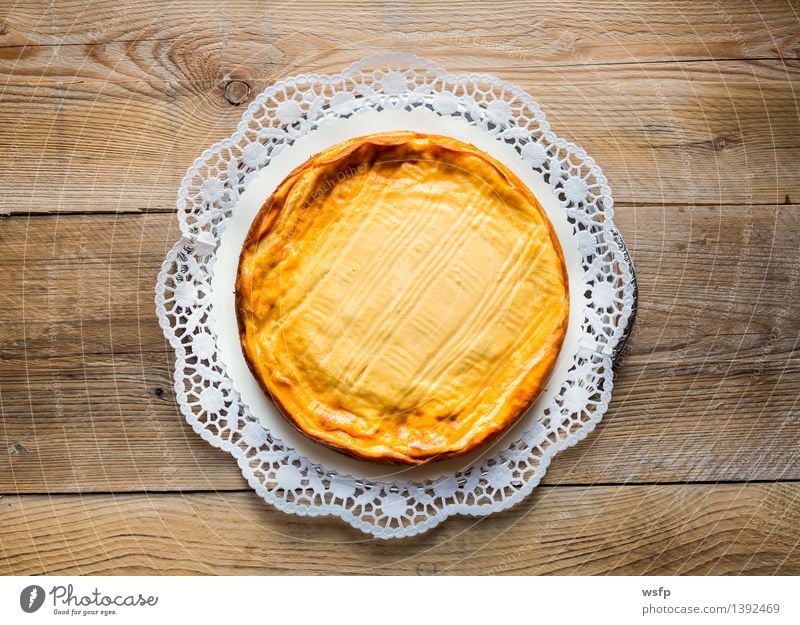 Käsekuchen auf rustikal Holz mit Tortenspitze Kuchen Dessert gelb Quarkkuchen Quarktorte Backwaren Biskuit Holztisch Landhaus Vogelperspektive süß Süßwaren rund