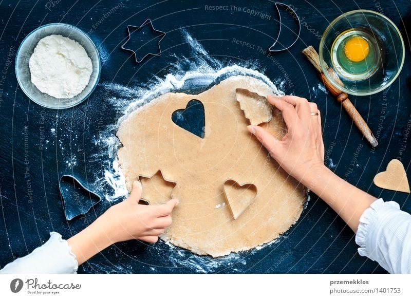 Mutter mit der Tochter, welche die Weihnachtssymbole im Teig ausschneidet Tisch Küche Mensch Mädchen Frau Erwachsene Hand machen geschnitten Teppichmesser Ei