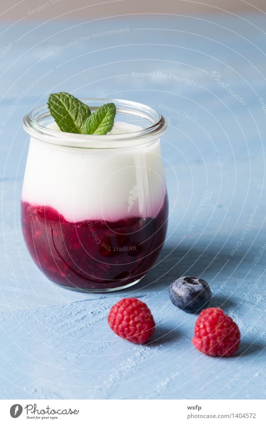 Rote Grütze mit Minze Joghurt Frucht Dessert Holz blau weiß rote Grütze Himbeeren Blaubeeren Blauer Holzhintergrund Glas Gesund Süsspeise Essen Holztisch Brett