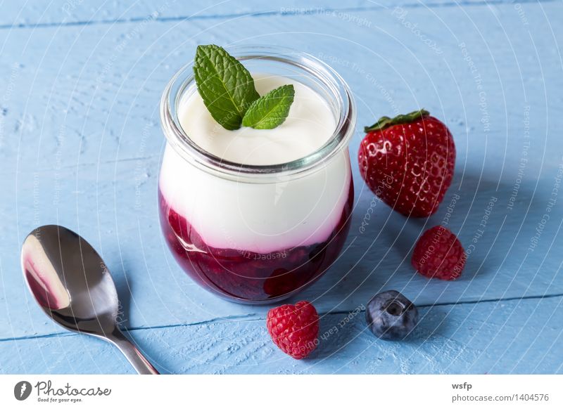 Rote Grütze mit Minze Joghurt Frucht Dessert Holz blau weiß rote Grütze Himbeeren Blaubeeren Blauer Holzhintergrund Erdbeeren Glas Gesund Süsspeise Essen