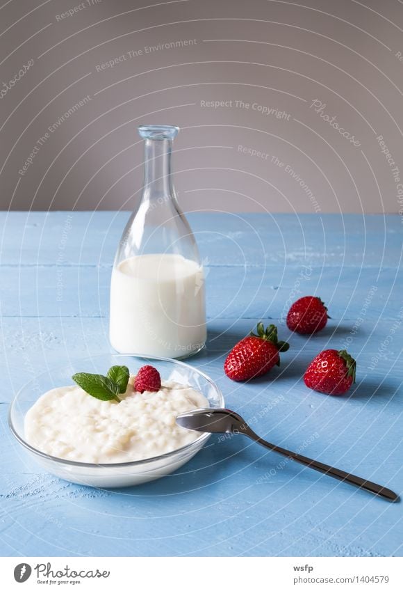 Milchreis mit Minze Frucht Dessert Löffel Holz blau weiß Dicker Reis Reisbrei Milchflasche Himbeeren Erdbeeren Blauer Holzhintergrund Gesund Süsspeise Essen