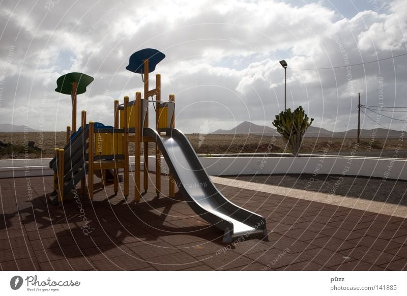 Spielplatz Spielen Kinderspiel Ferne Sommer Sonne Wolken Wärme Einsamkeit Rutsche Lanzarote Physik Kletteranlage Klettergerüst leer ruhig Farbfoto Außenaufnahme