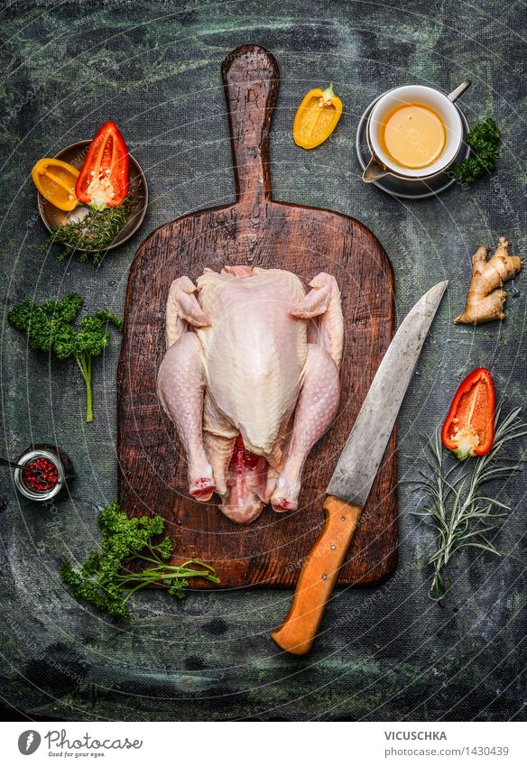 Ganzes Hähnchen auf altem Schneidebrett mit Zutaten Lebensmittel Fleisch Gemüse Kräuter & Gewürze Öl Mittagessen Abendessen Festessen Bioprodukte Diät