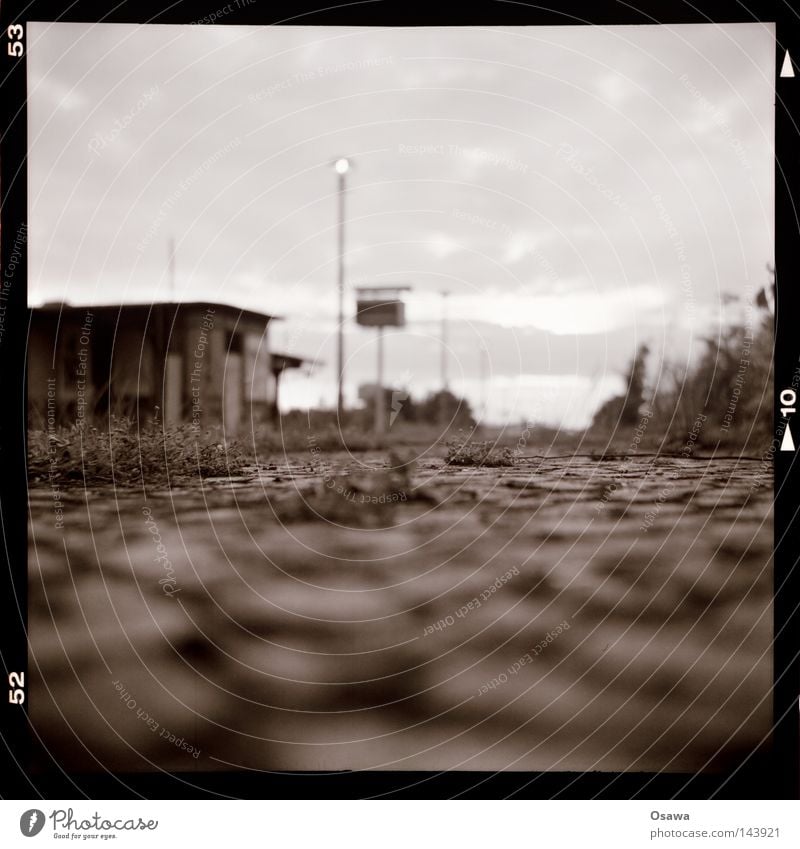 Ostkreuz 13 Lomografie Mittelformat Tiefenschärfe Haus Hütte Laterne Schwarzweißfoto Osten Bahnhof Bahnsteig Berlin Friedrichshain Kopfsteinpflaster Dach Abend