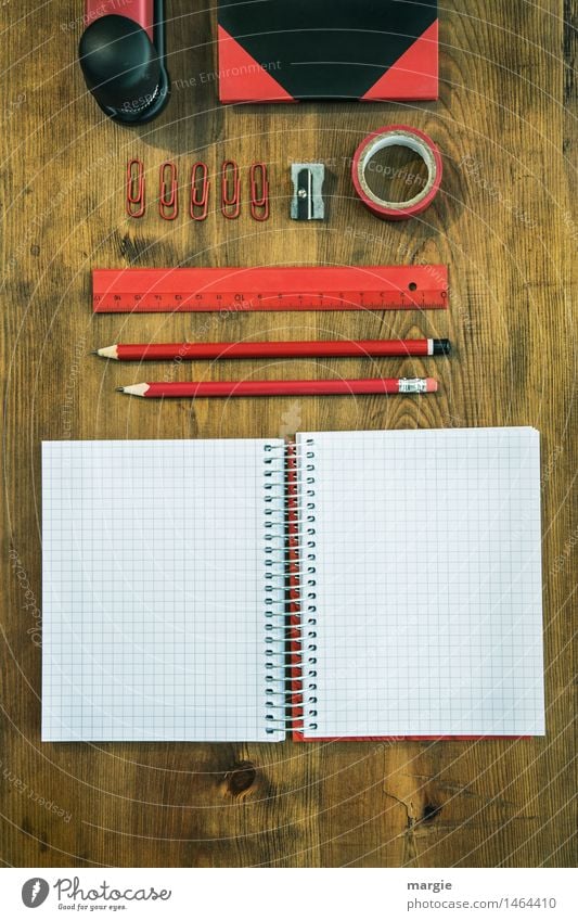 Rot- schwarze Schreibtisch Utensilien auf einem Holztisch. Heft, Bleistifte, Lineal, Klebeband, Spitzer, Büroklammern, Buch, Hefter Bildung Schule lernen