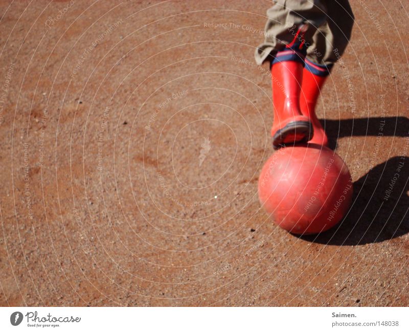 Fußball aus Leidenschaft Außenaufnahme Schatten Freude Spielen Ballsport Fußballplatz Energiewirtschaft Hose Stiefel Gummistiefel Armut dreckig rot Kraft Falte