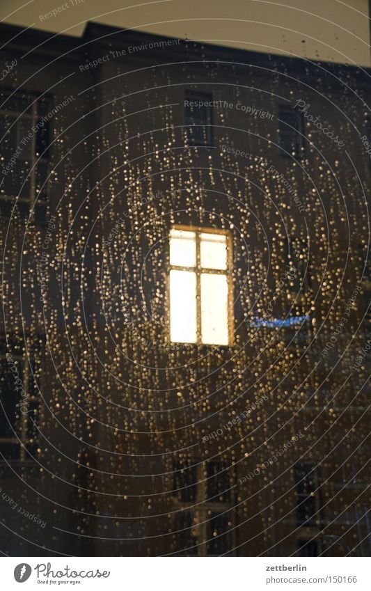 Fenster im Regen Fensterscheibe Scheibe Glas Glasscheibe Licht erleuchten Fensterkreuz Haus Stadthaus Hinterhof Abend Nacht dunkel Herbst Trauer Verzweiflung