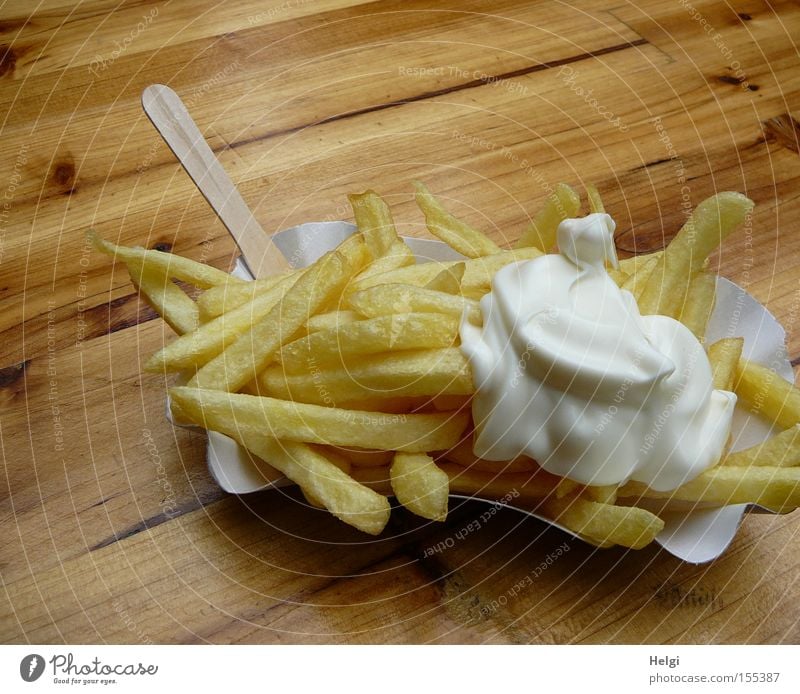 Portion Pommes mit Mayonnaise in einem Pappschälchen und einer Holzgabel auf einem Holztisch Farbfoto Außenaufnahme Textfreiraum oben Lebensmittel Ernährung