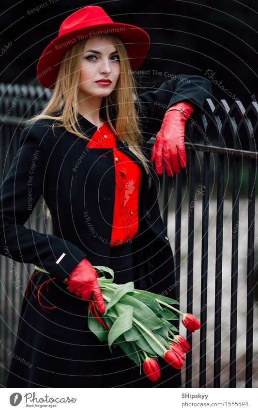 Frau, die auf dem Parkhintergrund mit Blumen steht elegant Stil schön Garten Mensch Mädchen Erwachsene Natur Wetter Tulpe Mode Bekleidung Pullover Pelzmantel