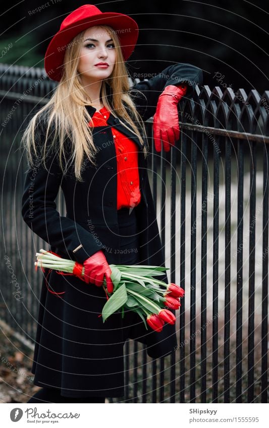 Frau, die auf dem Parkhintergrund mit Blumen steht elegant Stil schön Garten Mensch Mädchen Erwachsene Natur Wetter Tulpe Mode Bekleidung Pullover Pelzmantel