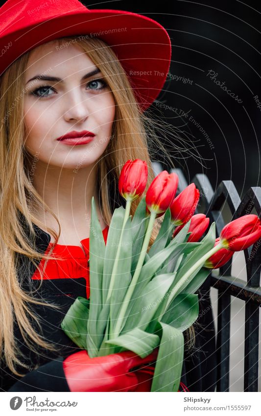 Frau, die auf dem Parkhintergrund mit Blumen steht elegant Stil schön Garten Mensch Mädchen Erwachsene Natur Wetter Tulpe Mode Bekleidung Pullover Pelzmantel