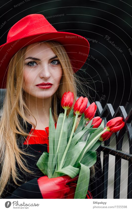 Frau, die auf dem Parkhintergrund mit Blumen steht elegant Stil schön Garten Mensch Mädchen Erwachsene Natur Wetter Tulpe Mode Bekleidung Pullover Pelzmantel