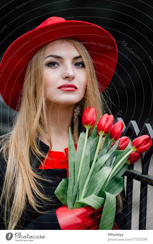 Frau, die auf dem Parkhintergrund mit Blumen steht elegant Stil schön Garten Mensch Mädchen Erwachsene Natur Wetter Tulpe Mode Bekleidung Pullover Pelzmantel