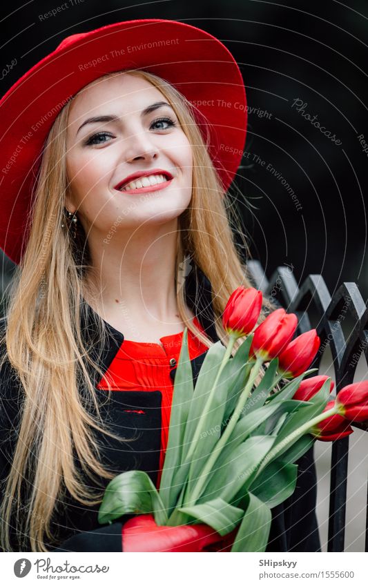 Frau, die auf dem Parkhintergrund mit Blumen steht elegant Stil schön Garten Mensch Mädchen Erwachsene Natur Wetter Tulpe Mode Bekleidung Pullover Pelzmantel