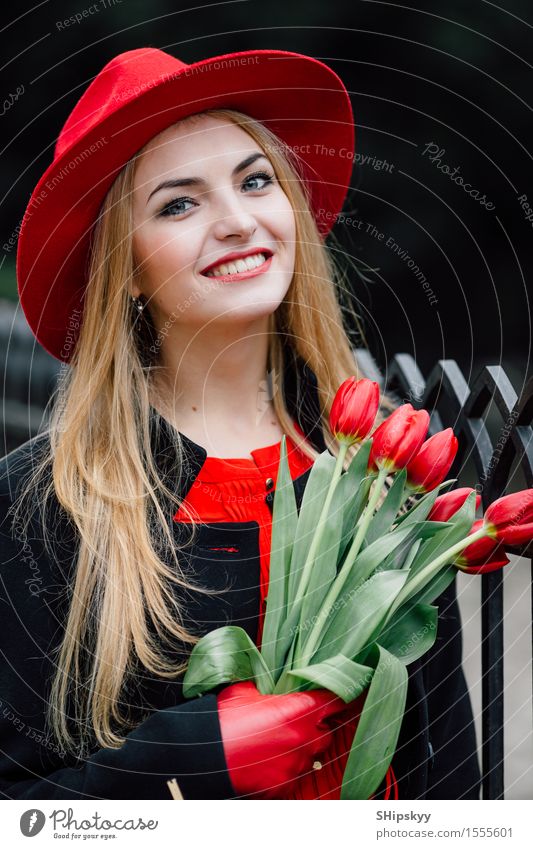 Frau, die auf dem Parkhintergrund mit Blumen steht elegant Stil schön Garten Mensch Mädchen Erwachsene Natur Wetter Tulpe Mode Bekleidung Pullover Pelzmantel