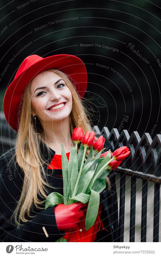 Frau, die auf dem Parkhintergrund mit Blumen steht elegant Stil schön Garten Mensch Mädchen Erwachsene Natur Wetter Tulpe Mode Bekleidung Pullover Pelzmantel