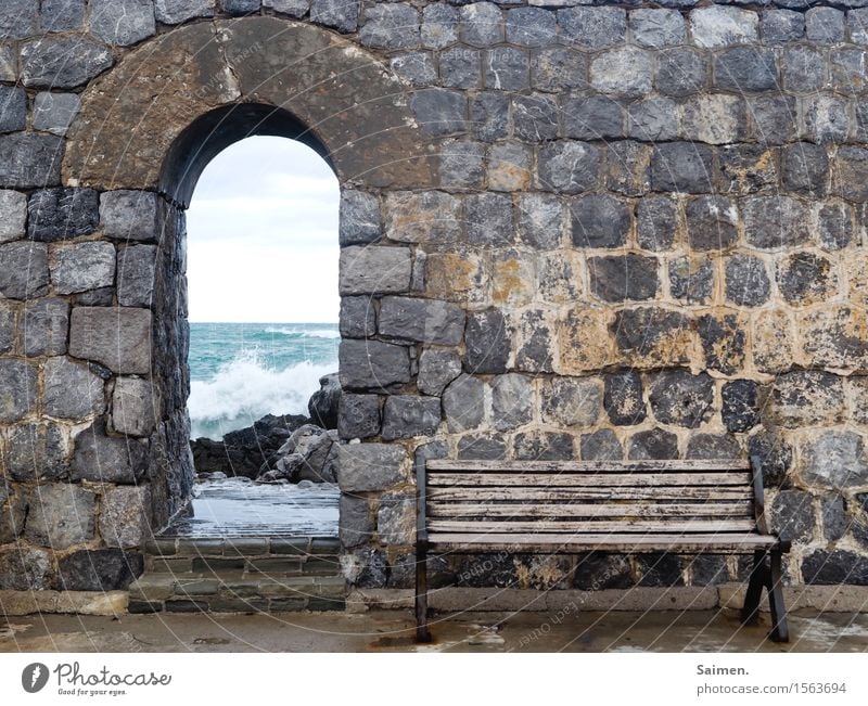 Bank am Meer vor Mauer Ozean Sitzbank Felsen Steine Stadtmauer Italien Mittelmeer Wellen Brandung Detail Küste Gischt Natur nass Farbfoto Strand Himmel