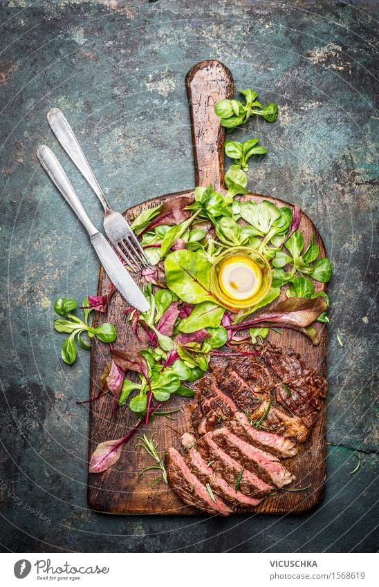 Grillsteak mit grünem Salat und Besteck auf Schneidebrett Lebensmittel Fisch Salatbeilage Kräuter & Gewürze Öl Ernährung Mittagessen Abendessen Picknick