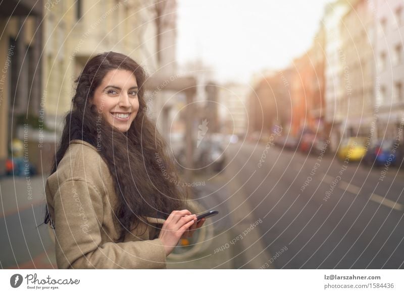 Brunettefrau, die an ihrem Handy simst Lifestyle Gesicht Business Telefon PDA Frau Erwachsene 1 Mensch 18-30 Jahre Jugendliche Herbst Straße brünett Lächeln