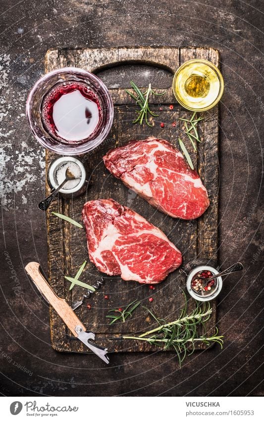 Zwei rohe Rindersteaks mit Glas Wein , Kräuter, Öl und Gewürze. Fleisch Kräuter & Gewürze Ernährung Mittagessen Abendessen Büffet Brunch Festessen Bioprodukte