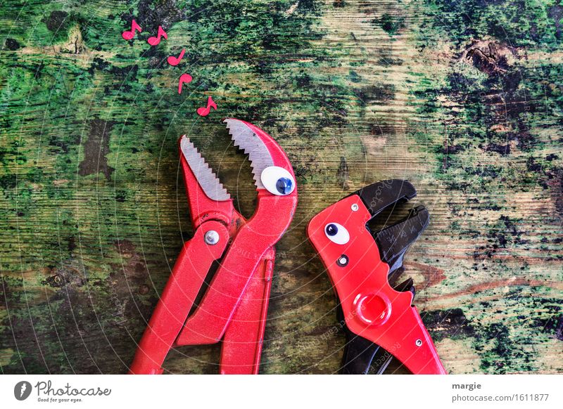 Singst du mir mein Lied? Zwei rote Zangen mit Augen auf einem alten Holztisch mit roten Musik - Noten Handwerker Arbeitsplatz Baustelle Dienstleistungsgewerbe