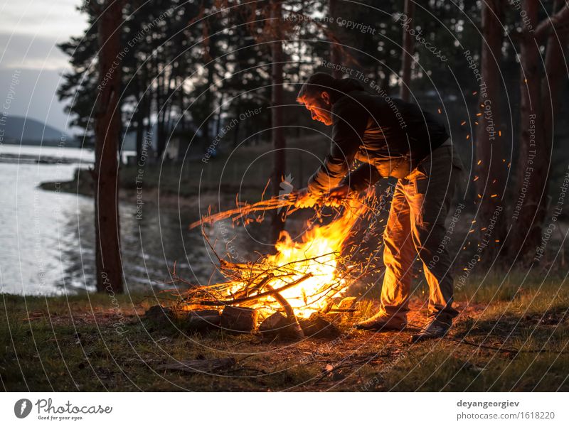 Mann beleuchtet ein Feuer im Kamin in der Natur nachts Freizeit & Hobby Ferien & Urlaub & Reisen Tourismus Abenteuer Camping Sommer Berge u. Gebirge wandern