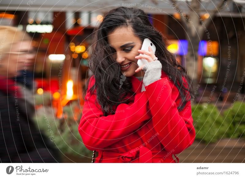 Frau in rotem Mantel mit Handy in der Hand, Smartphone, Stadtszene Telefon Lächeln Lifestyle Mädchen Mobile Person kalt Winter Technik & Technologie Zelle