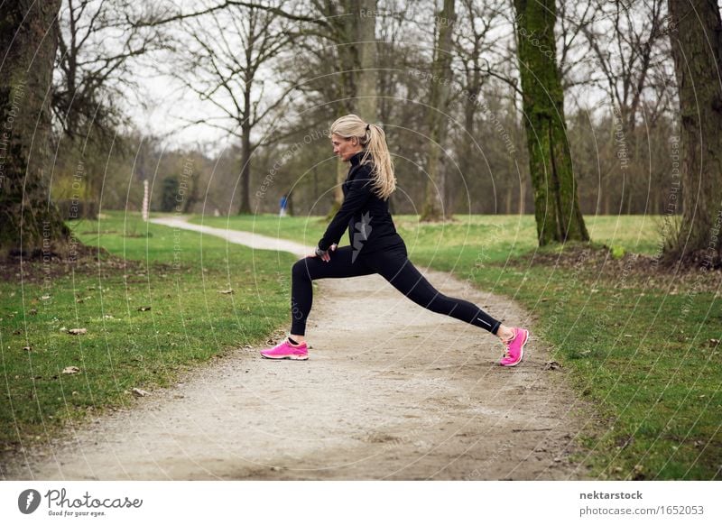 attarcive Frau, die sich im Park ausdehnt. Lifestyle Körper Wellness Winter Sport Mensch Erwachsene Baum Wege & Pfade Fitness sportlich üben Gesundheit Training