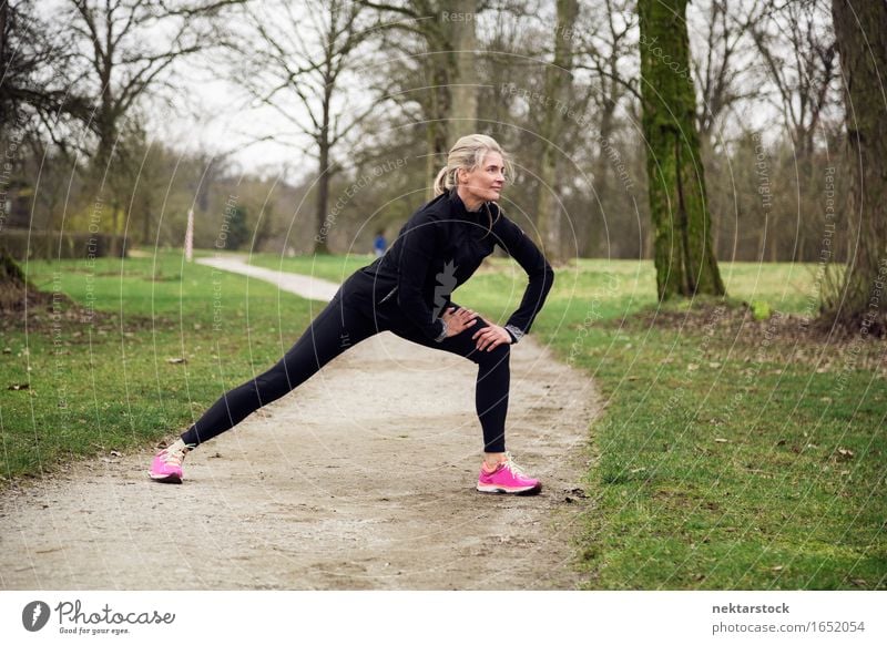 attarcive Frau, die sich im Park ausdehnt. Lifestyle Körper Wellness Winter Sport Mensch Erwachsene Baum Wege & Pfade Fitness sportlich üben Gesundheit Training