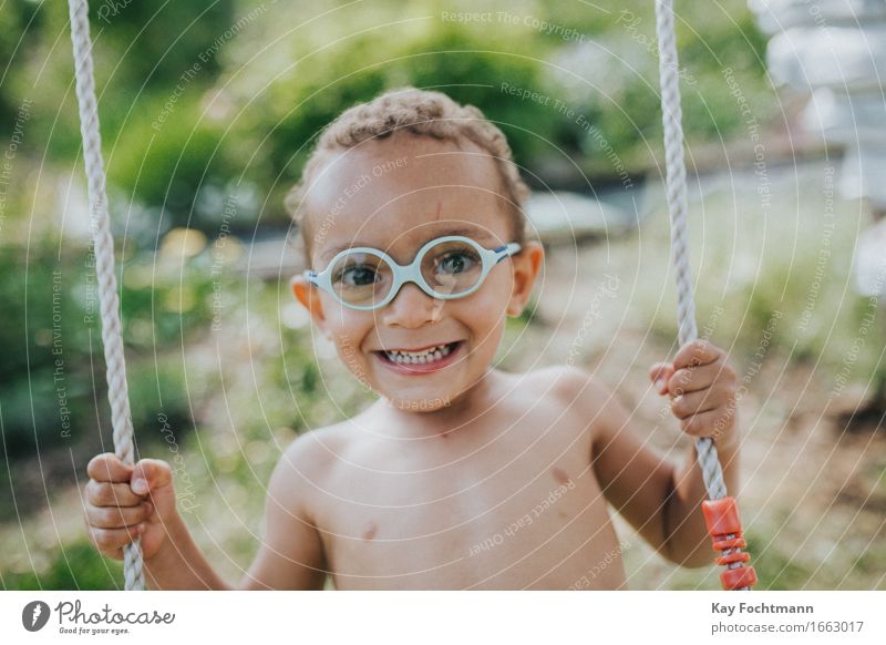 young boy on a swing Freude Glück Leben Wohlgefühl Sommer Sommerurlaub Häusliches Leben Garten Mensch Kleinkind Kindheit 1 1-3 Jahre Brille kurzhaarig Locken