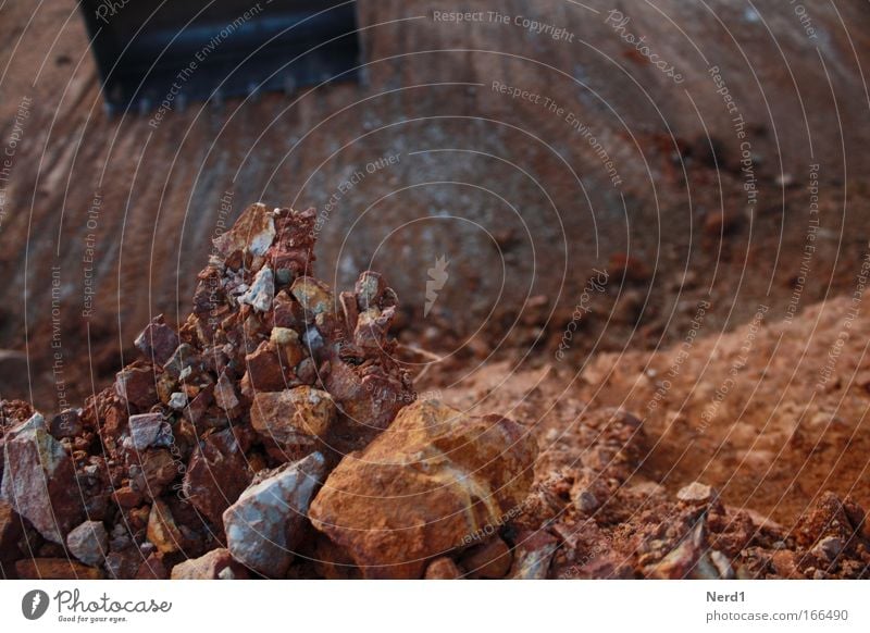 Schaufelbagger Farbfoto Außenaufnahme Detailaufnahme Menschenleer Kontrast Sonnenlicht Schwache Tiefenschärfe Baustelle Maschine Fahrzeug Stein Bruchstein