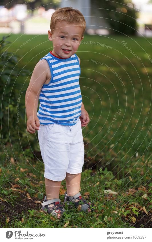 Porträt von 3 Jahre altem Jungen in gestreifter Weste im Stadtpark, der zum Fotografen schaut und lächelt Lifestyle Freude Glück schön Gesicht Freizeit & Hobby