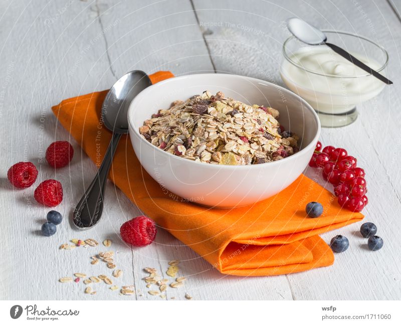 Müsli mit Joghurt und Früchten auf Holz Frucht Frühstück orange Zerealien Früchtemüsli Haferflocken Himbeer Johannisbeeren Blaubeeren Minze weißer Holztisch