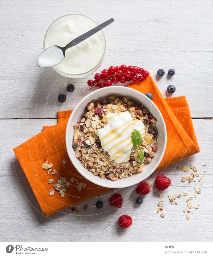 Müsli mit Joghurt und Früchten auf Holz Frucht Frühstück orange Zerealien Früchtemüsli Haferflocken Honig Himbeer Johannisbeeren Blaubeeren Minze