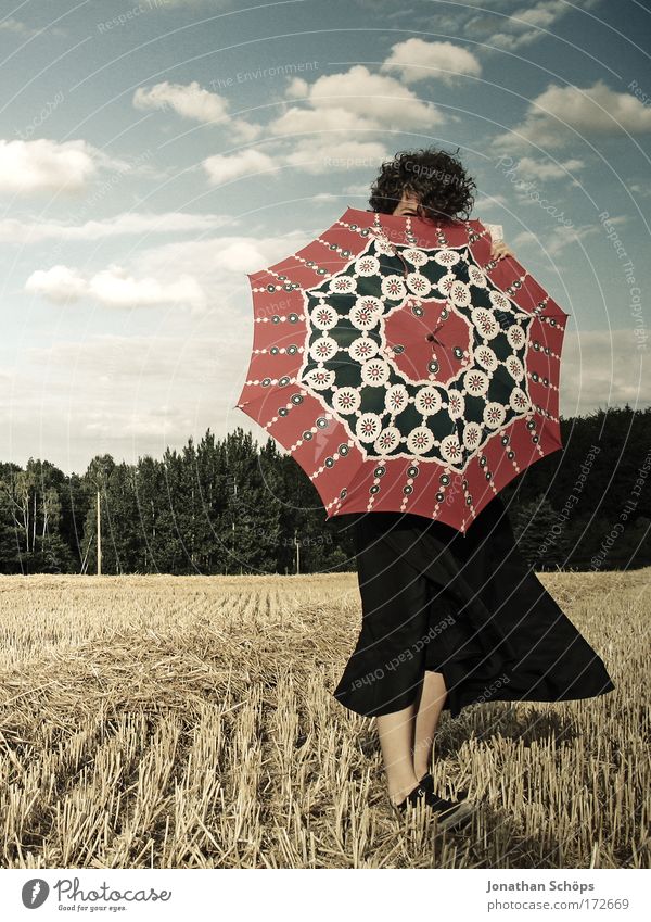 junge Frau in schwarz zeigt mit Schirm nach vorne vor Wolkenhimmel Lifestyle elegant Stil Freude Glück schön Sommer Sommerurlaub Tanzen Mensch feminin