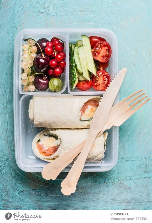 Gesundes Mittagessen Box mit Tortilla Wraps und Holzbesteck Lebensmittel Fisch Gemüse Salat Salatbeilage Frucht Ernährung Festessen Bioprodukte