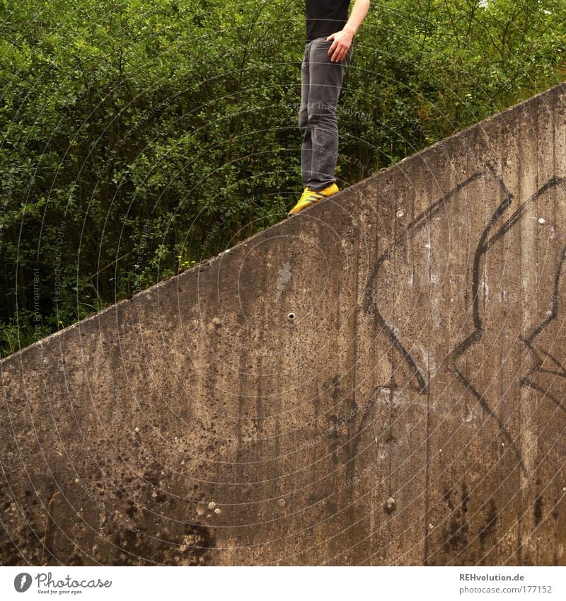 von links nach schräg Farbfoto Gedeckte Farben Außenaufnahme Textfreiraum unten Mensch maskulin Junger Mann Jugendliche Erwachsene 1 18-30 Jahre Mauer Wand Hose