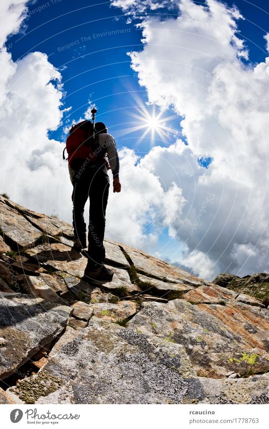 Mann, der oben einen Felsenhügel gegen einen drastischen bewölkten Himmel wandert Lifestyle Freude Ferien & Urlaub & Reisen Tourismus Abenteuer Expedition