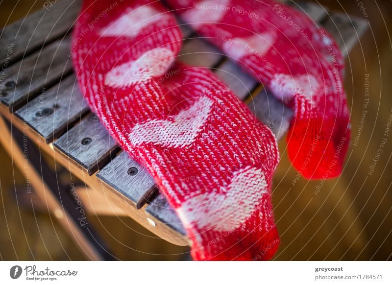 Nahaufnahme von roten gestrickten Socken mit niedlichen Herz-Muster auf Holzstuhl Möbel Stuhl Frau Erwachsene Wärme Bekleidung Schuhe Liebe hell Mut Romantik