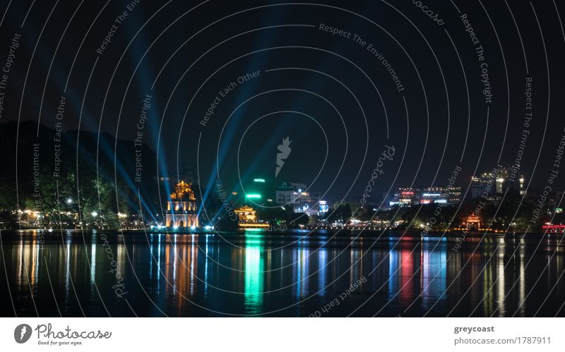 Hanoi Ansicht bei Nacht mit beleuchtetem Schildkrötenturm und Hoan Kiem See im Stadtzentrum. Bunte Lichter spiegeln sich im dunklen Wasser