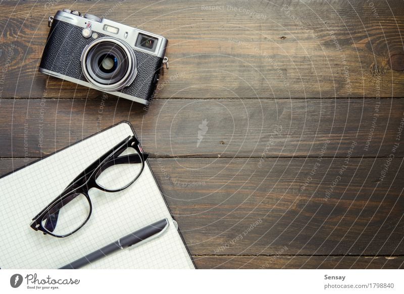 Kamera, Brille und Notizblock auf Holz Stil Design Schreibtisch Tisch Büro Business Fotokamera Papier Schreibstift alt oben retro Top Hintergrund altehrwürdig