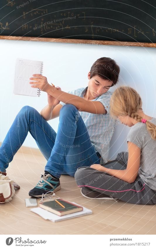 Teenager sitzen unter einer Tafel lernen in der Schule Bildung Klassenraum Schulkind Schüler Studium Student Funktelefon Computer Notebook Mensch Mädchen Junge