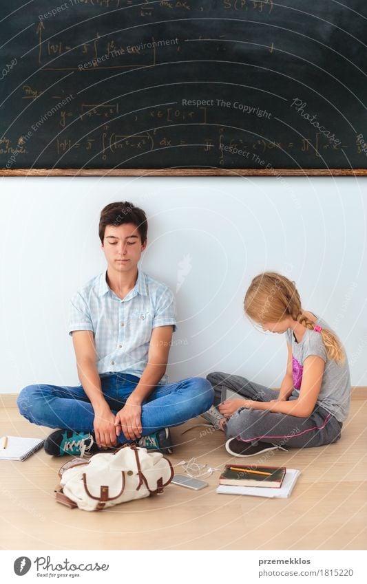 Jugendliche, die in der Schule an einer Tafel sitzen Klassenraum Schulkind Studium Arbeitsplatz Handy Notebook Werkzeug Mensch Mädchen Junge 2 13-18 Jahre Buch