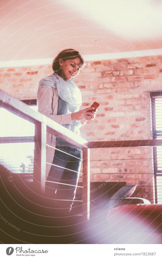 Kaukasische Frau, die an ihrem Smartphone lächelt Freude lesen Wohnzimmer Arbeit & Erwerbstätigkeit Büro Business Handy PDA Technik & Technologie