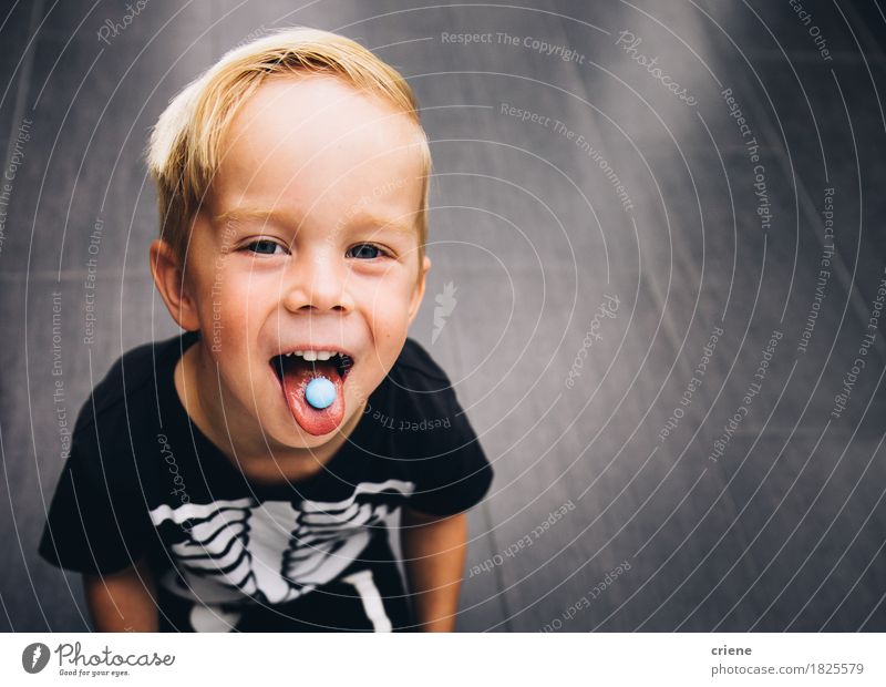 Unverschämter kleiner Junge, der heraus Zunge beim Essen von Bonbons ausdehnt Lebensmittel Süßwaren Lifestyle Freude Kind Kleinkind Kindheit Mund genießen