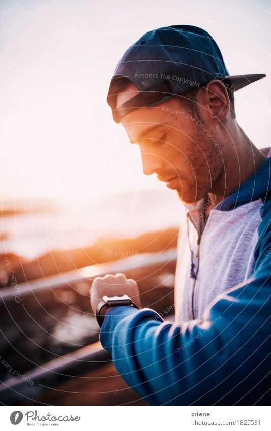 Junger kaukasischer erwachsener Mann, der auf seiner intelligenten Uhr Sonnenuntergang betrachtet Lifestyle Sommer Technik & Technologie Internet Mensch