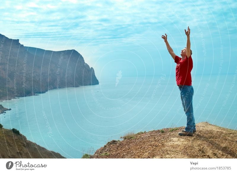 Glücklicher Mann, der oben auf der Klippe mit den Händen steht Lifestyle Freude Ferien & Urlaub & Reisen Abenteuer Freiheit Sonne Meer Berge u. Gebirge Erfolg