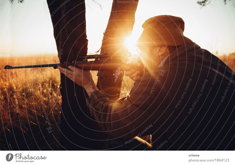 Jäger, der hinter Baum auf dem Feldschießen des wilden Tieres sich versteckt Fleisch Lifestyle Freizeit & Hobby Jagd Sport Erfolg maskulin Mann Erwachsene